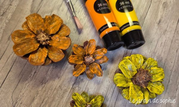 Fleurs en pommes de pin peintes en orange et jaune avec tubes de peinture acrylique et pinceau